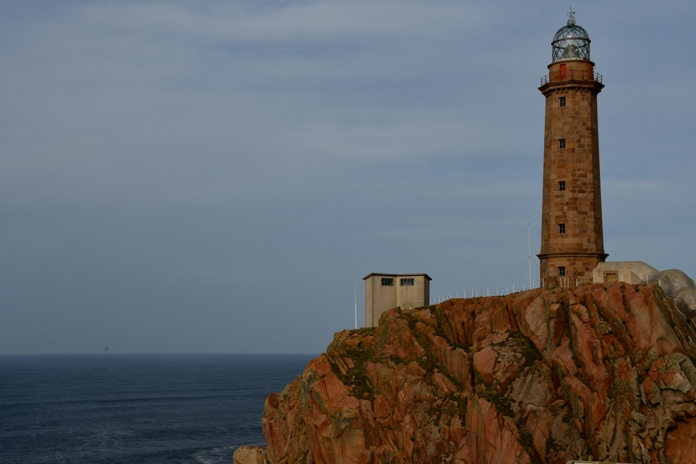 Leuchtturm auf Felsen Haeuschen Meer