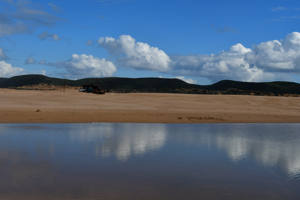 Wasser am Sandstrand gruene Huegel