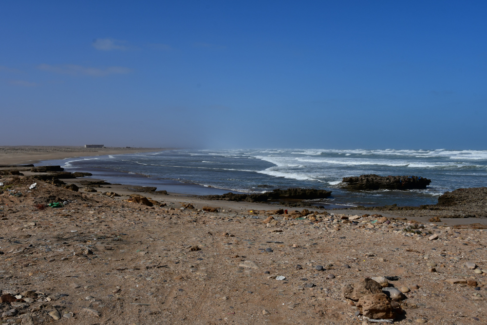 flacher Steinstrand Muell Wellen Atlantik