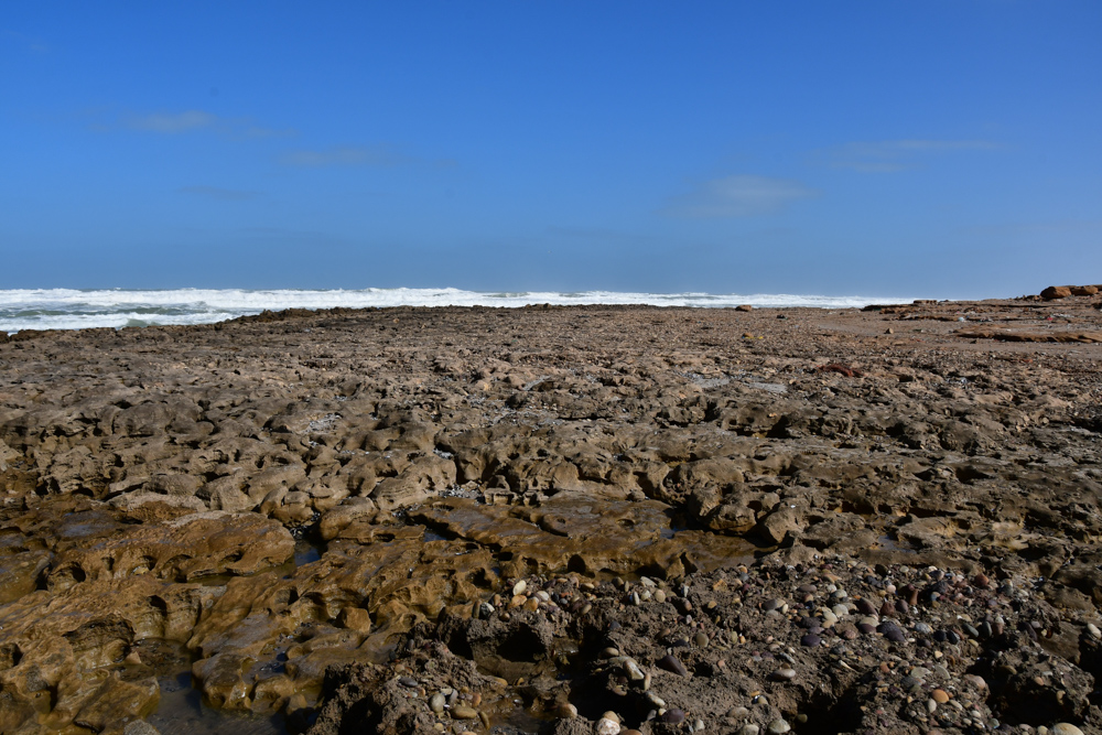 zerfurchte flache Felsen Strand Welle